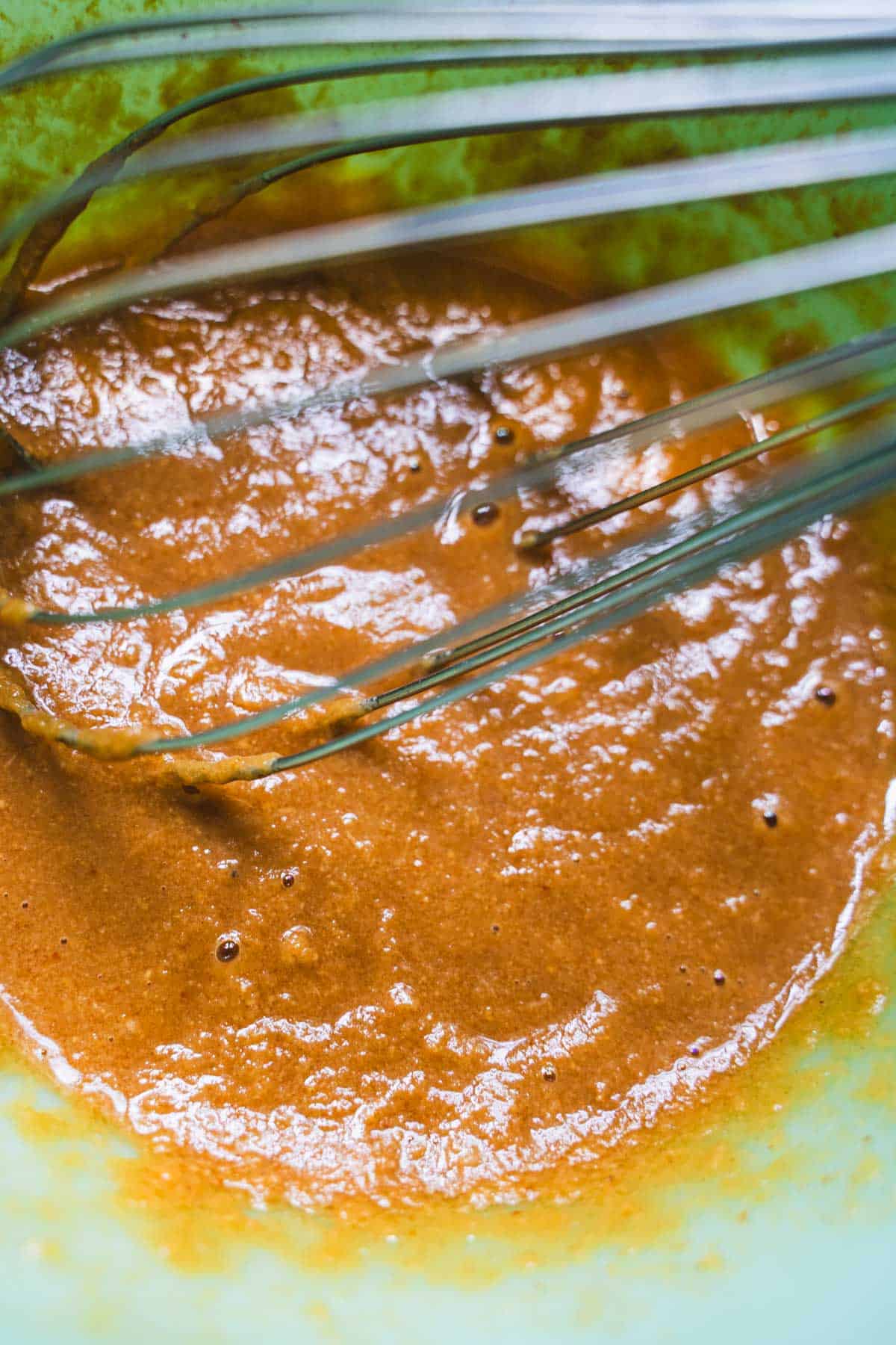Asian peanut sauce ingredients whisked together in a green glass bowl for dumpling potsticker dinner for two.