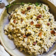 Mushroom salad in a tan bowl garnished with bacon bits and black salt.