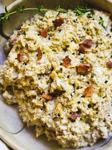 Mushroom salad in a tan bowl garnished with bacon bits and black salt.