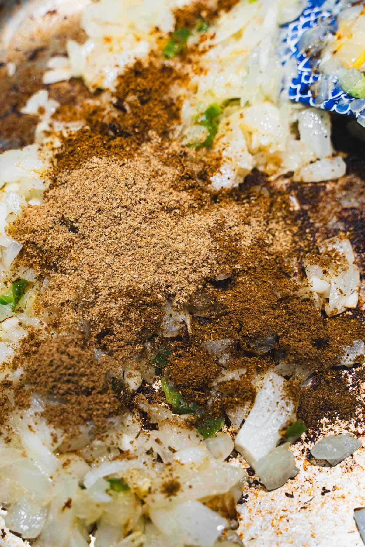 Dry spices added to softened onion mixture in saute pan to build the butter chicken sauce.