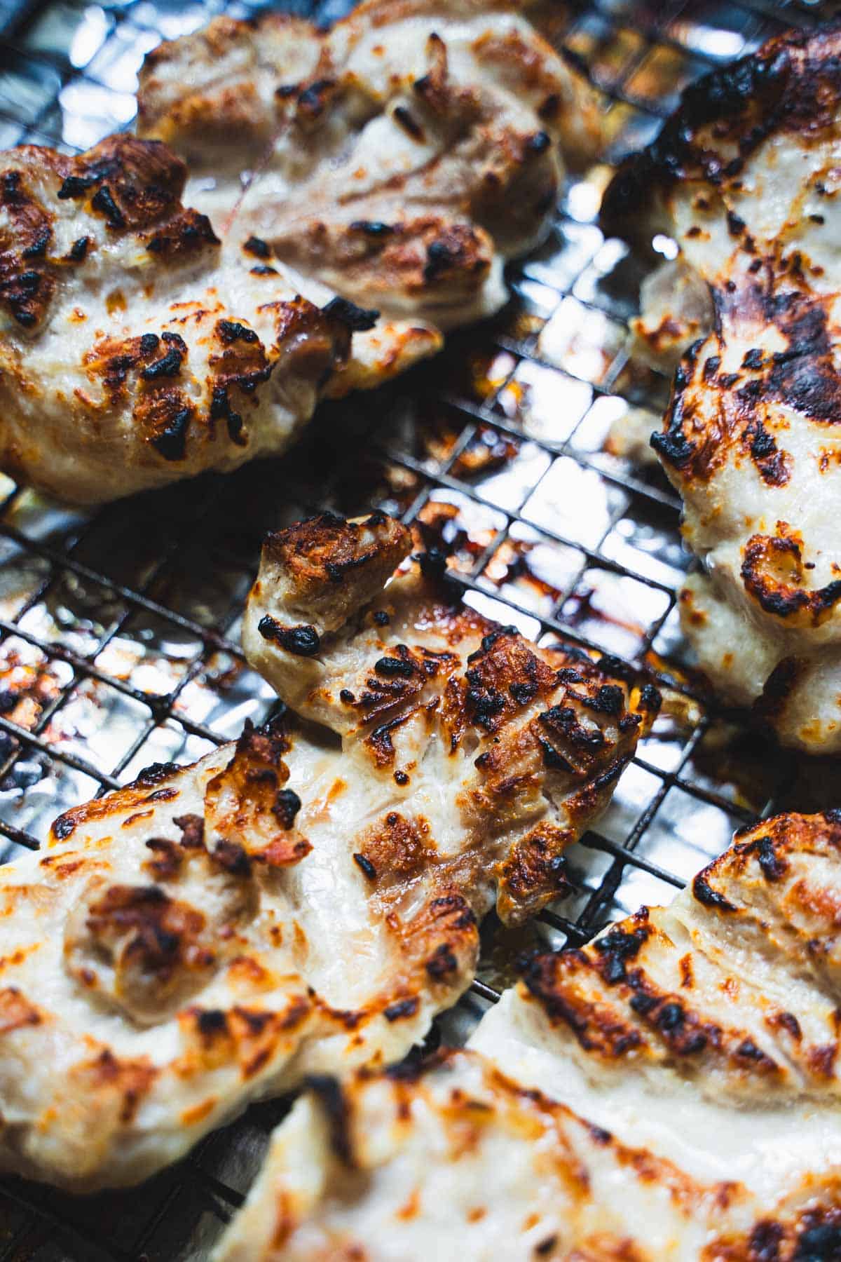 Chicken thighs on wire rack that have been broiled.