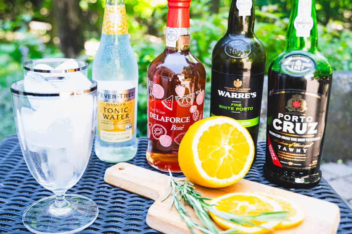 Three types of port, the garnish and glasses of ice on a black table to make an easy summer cocktail of port and tonic.