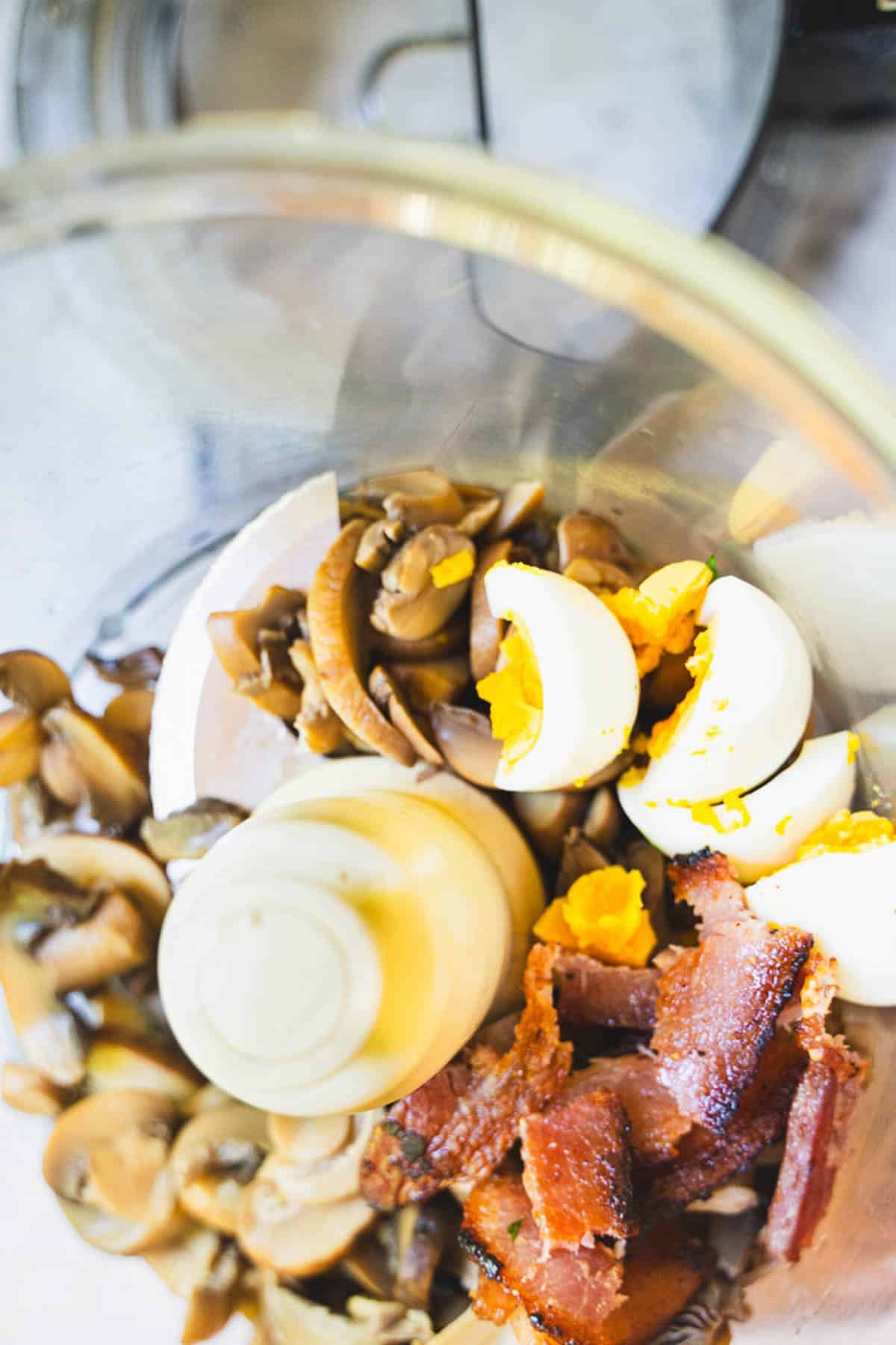 Mushrooms, egg and bacon in a food processor bowl.