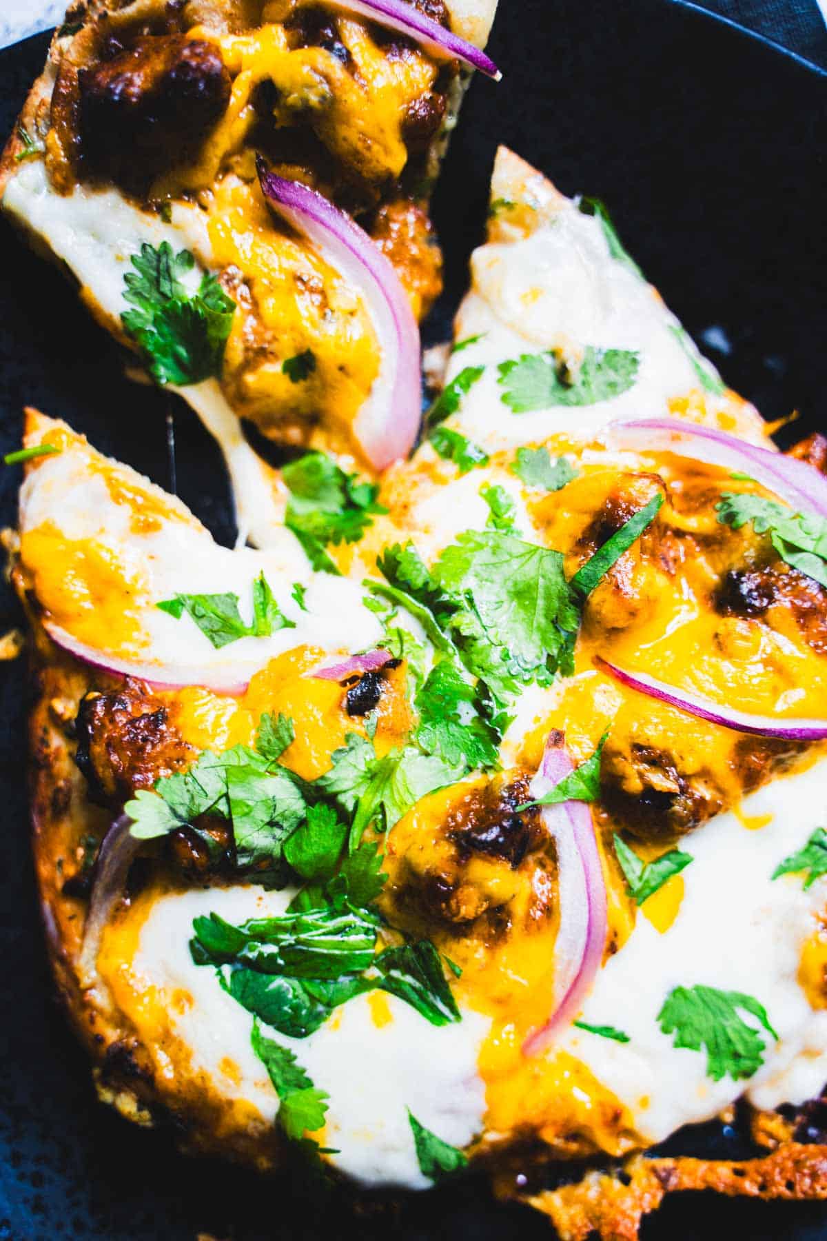 Naan and Butter Chicken Pizza slice being pulled away from the whole pizza.