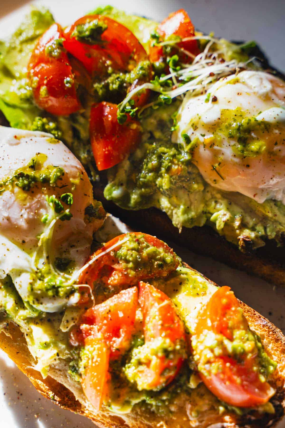 Thick slices of country bread topped with smashed avocado, marinated tomatoes and poached egg.