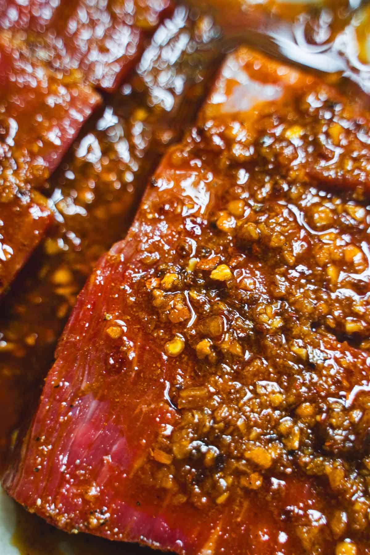 flank steak marinating in a chili crisp sauce before pan frying.