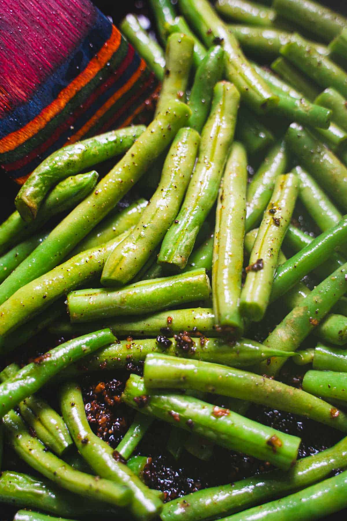 Green beans in cast iron skillet tossed with chili crisp for beef and noodles recipe.