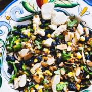 Wheat berry and wild rice grain bowl with pickled corn and blueberries in a decorated bowl and a salad bowl with wheat berries and wild rice in glass jars.