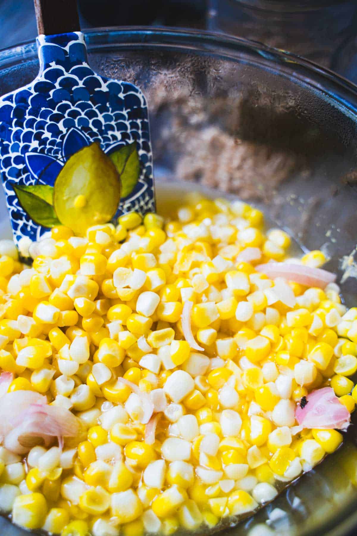 Pickled corn and shallots in a glass bowl to make a grain bowl.