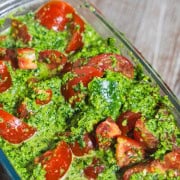 Marinated tomatoes in a glass rectangle loaf pan on wooden table.