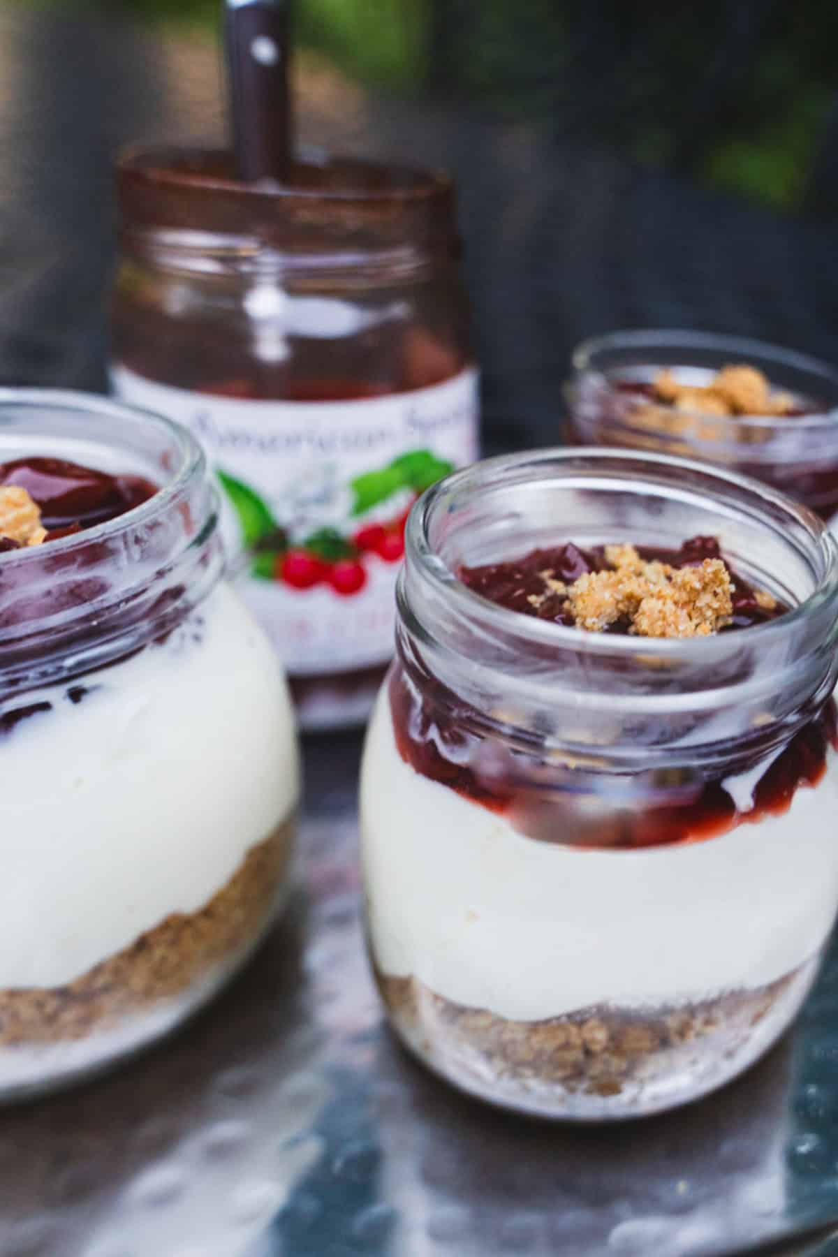 No bake cheese cake dessert in clear glass mason jars.
