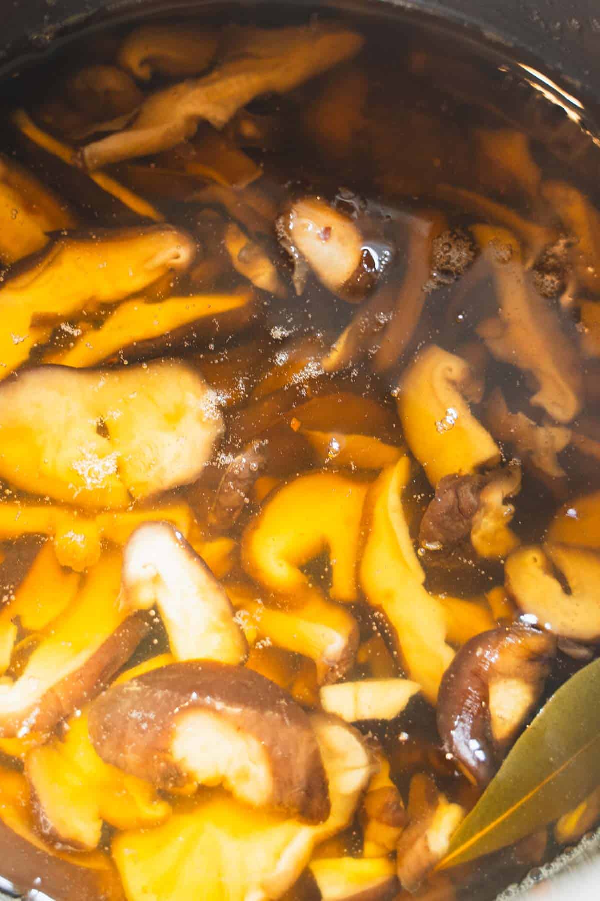 Simmering mushrooms in spiced pickling brine in a sauce pan.