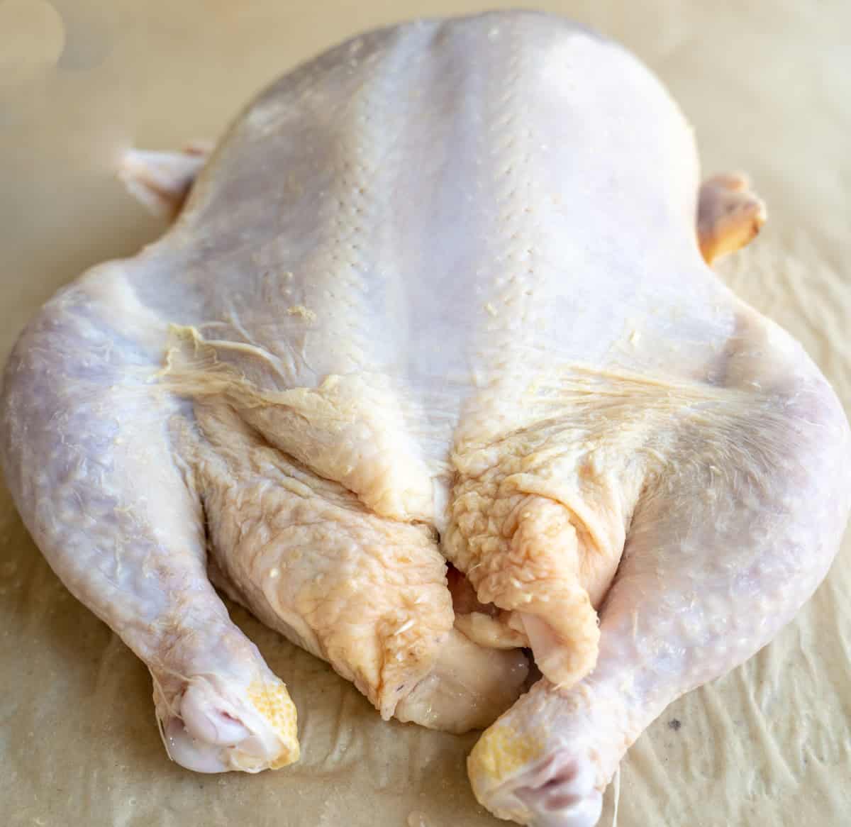 whole chicken on cutting board with legs facing you.