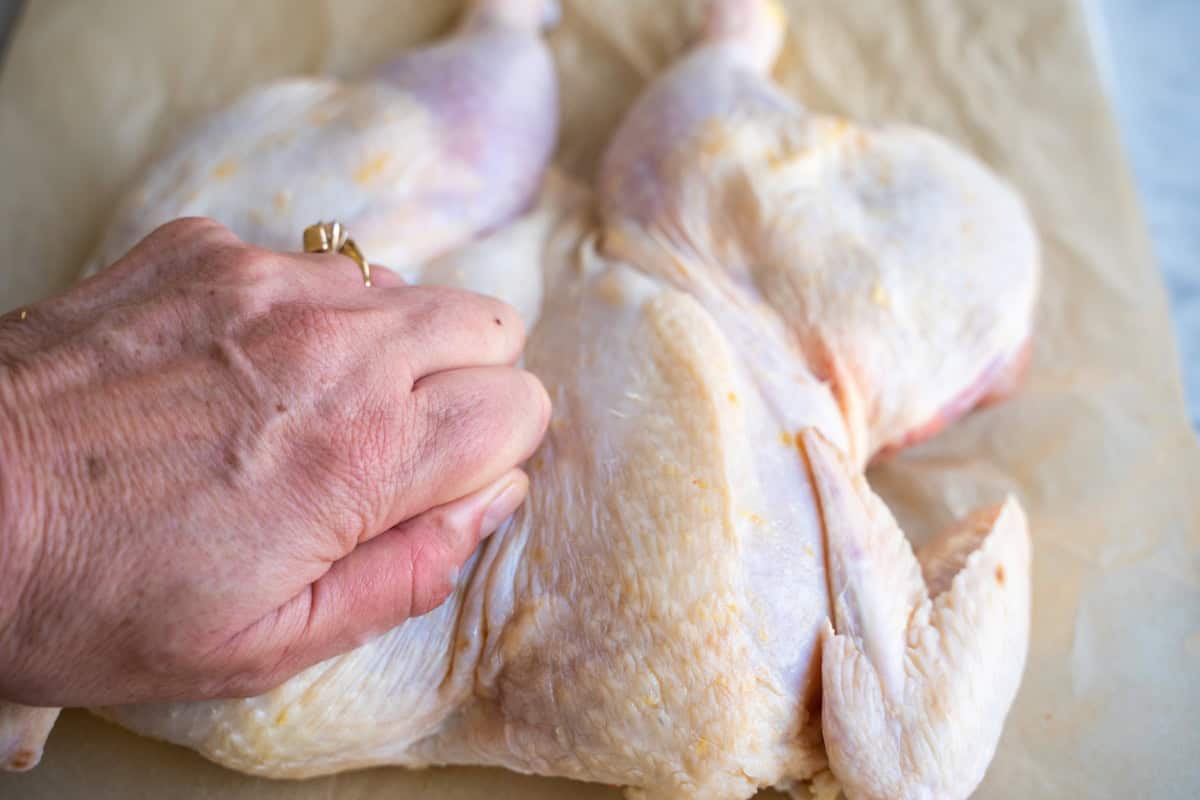 Hand pressing chicken flat.