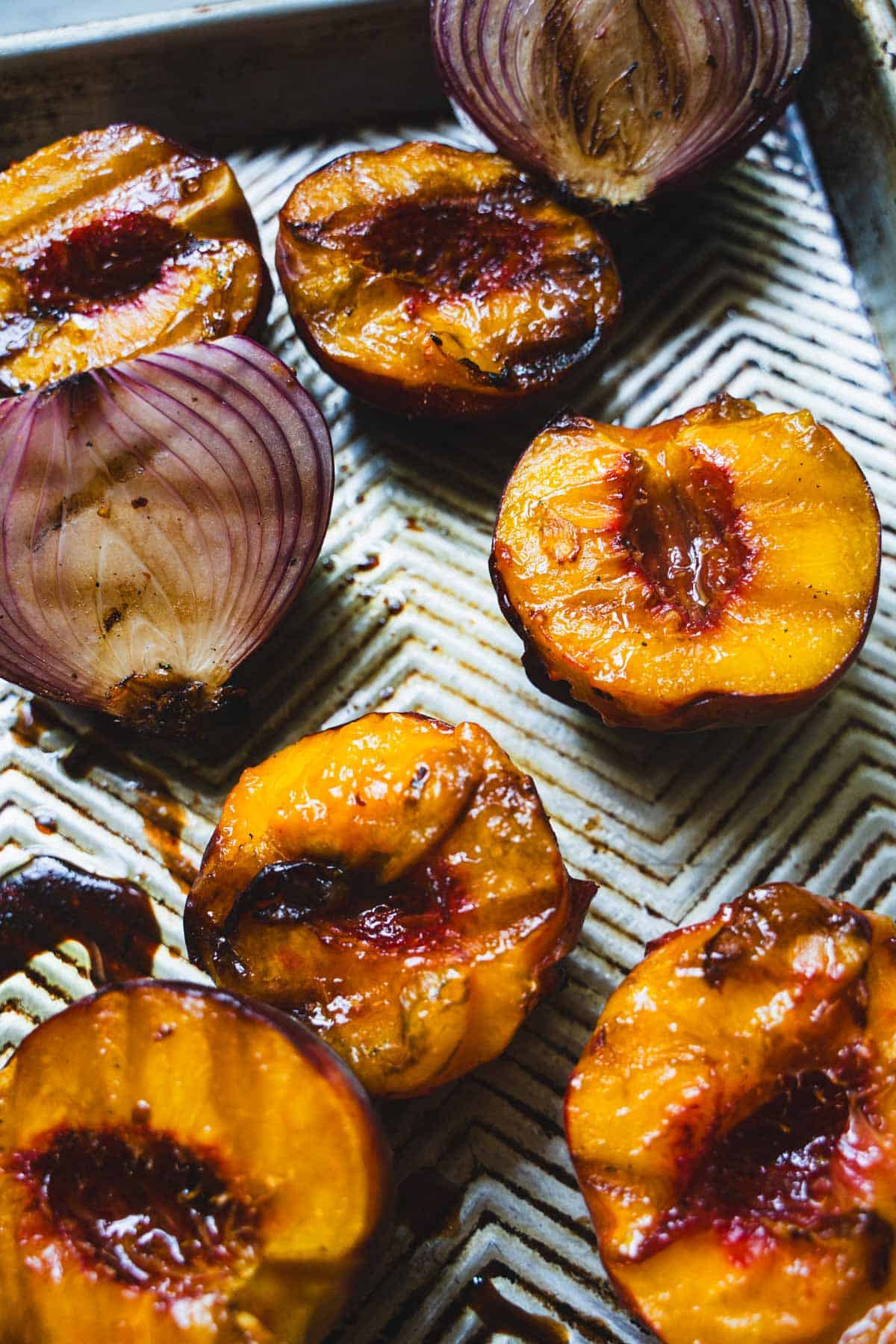 Grilled peaches on a baking sheet for balsamic grilled spatchcock chicken with peaches.