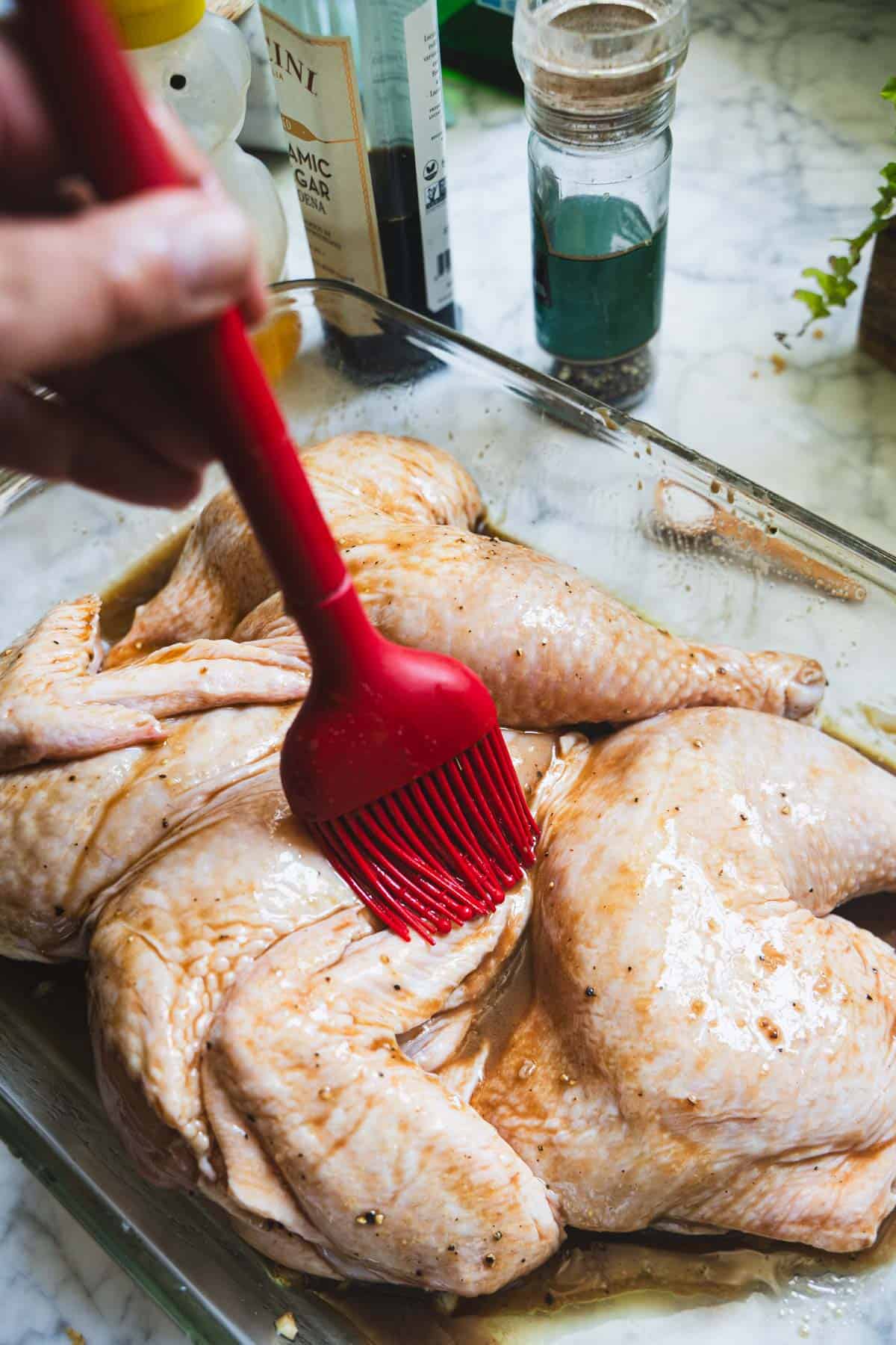 Balsamic marinade for spatchcock chicken being brushed onto the chicken.