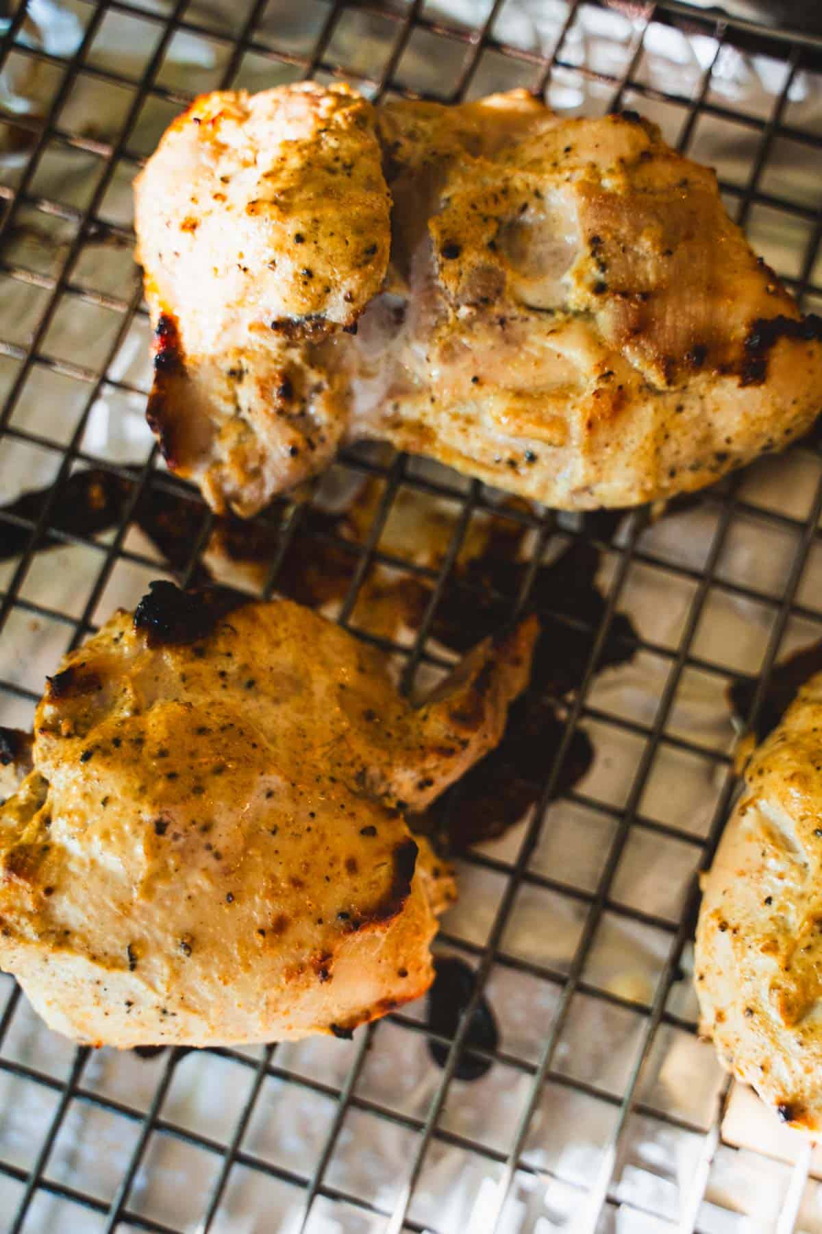 Broiled halal chicken on a wire rack.