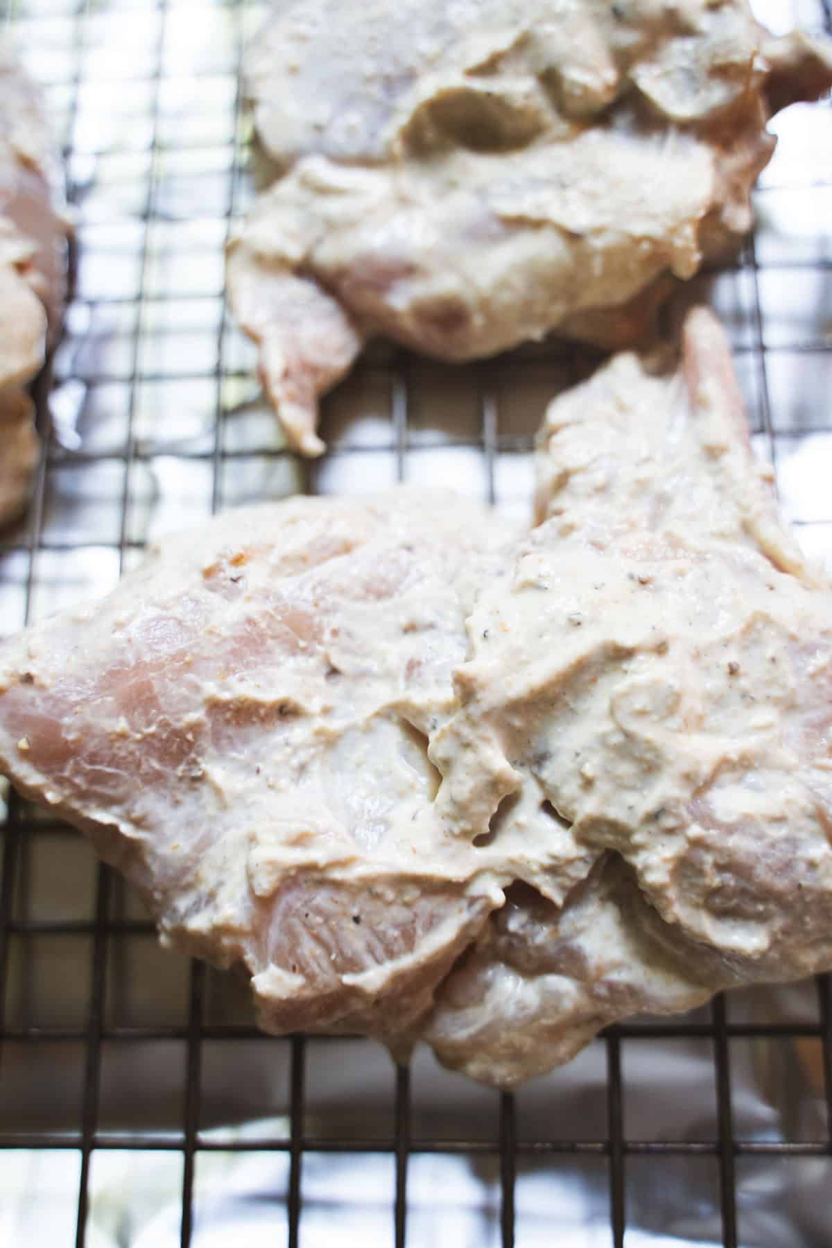 yogurt marinaded chicken thighs on a baking rack for halal chicken and yellow rice.
