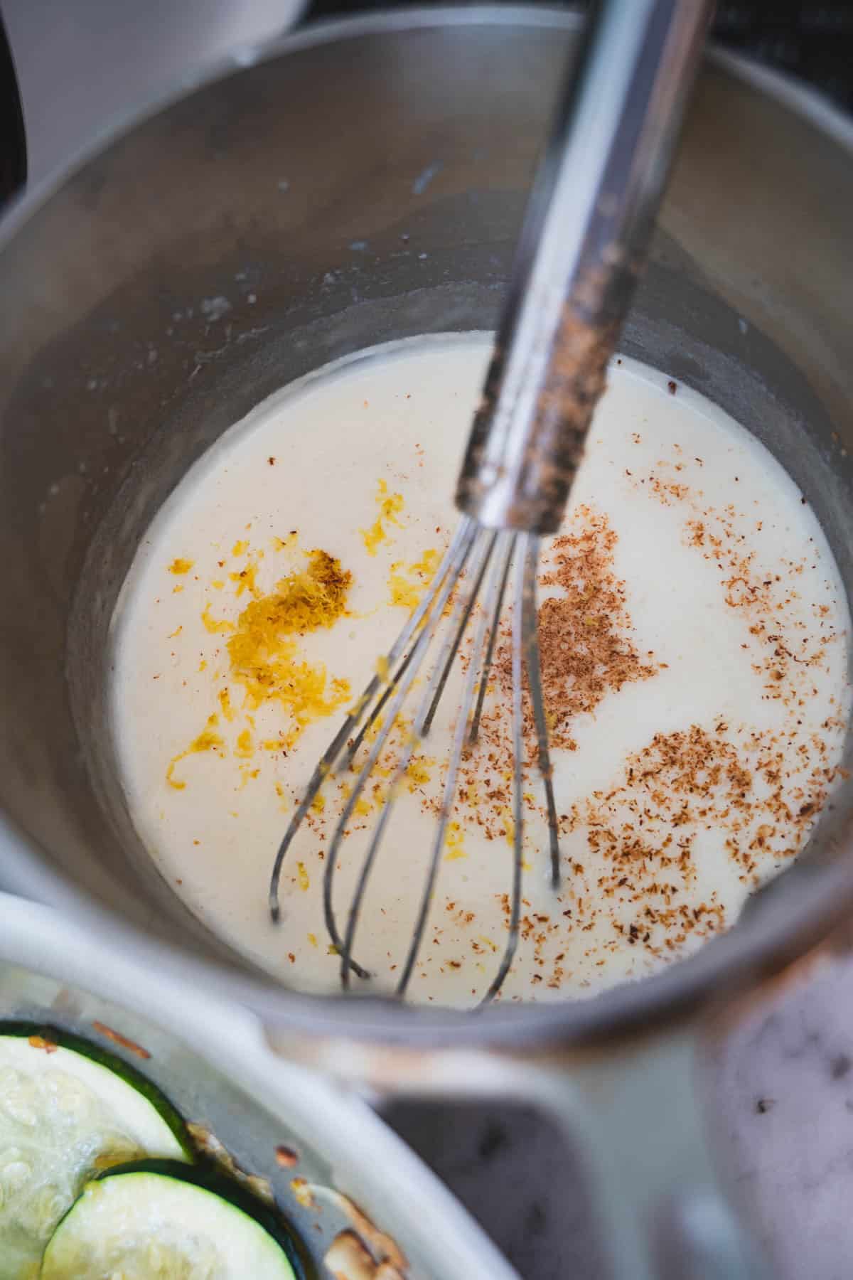 Lemon bechamel sauce in sauce pan with whisk.