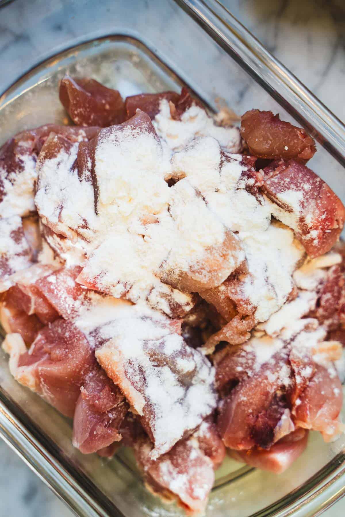 Chicken thighs coated in baking powder and salt in a baking dish.