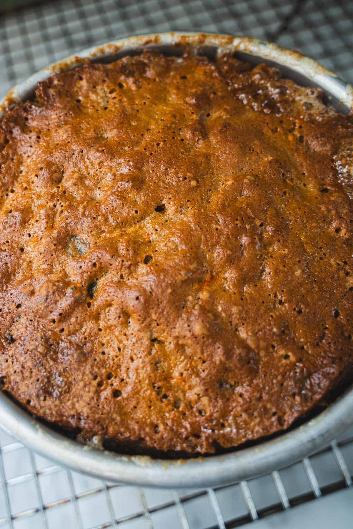 Baked upside down carrot cake in 6-inch round cake pan on wire rack.