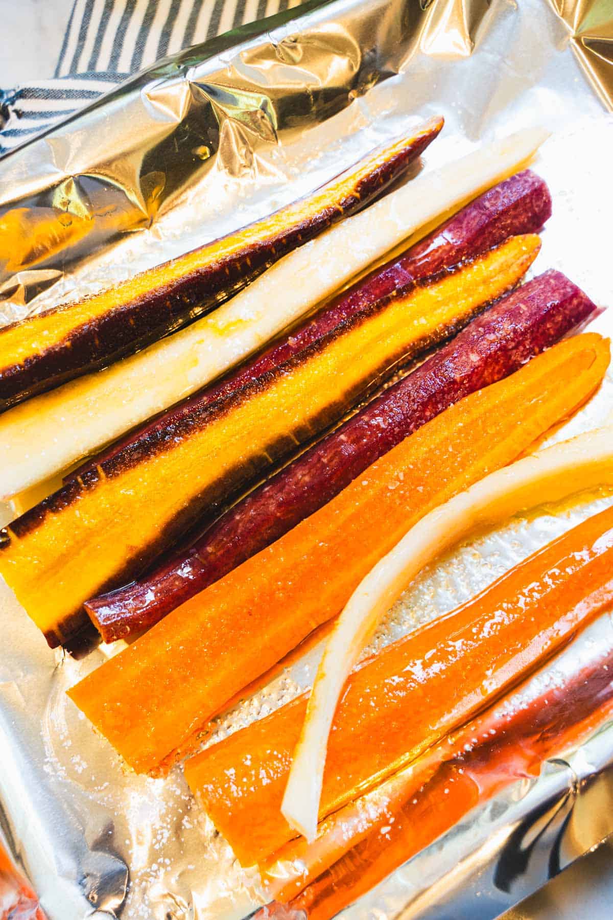 Mixed colors of carrots on a foil lined baking sheet.