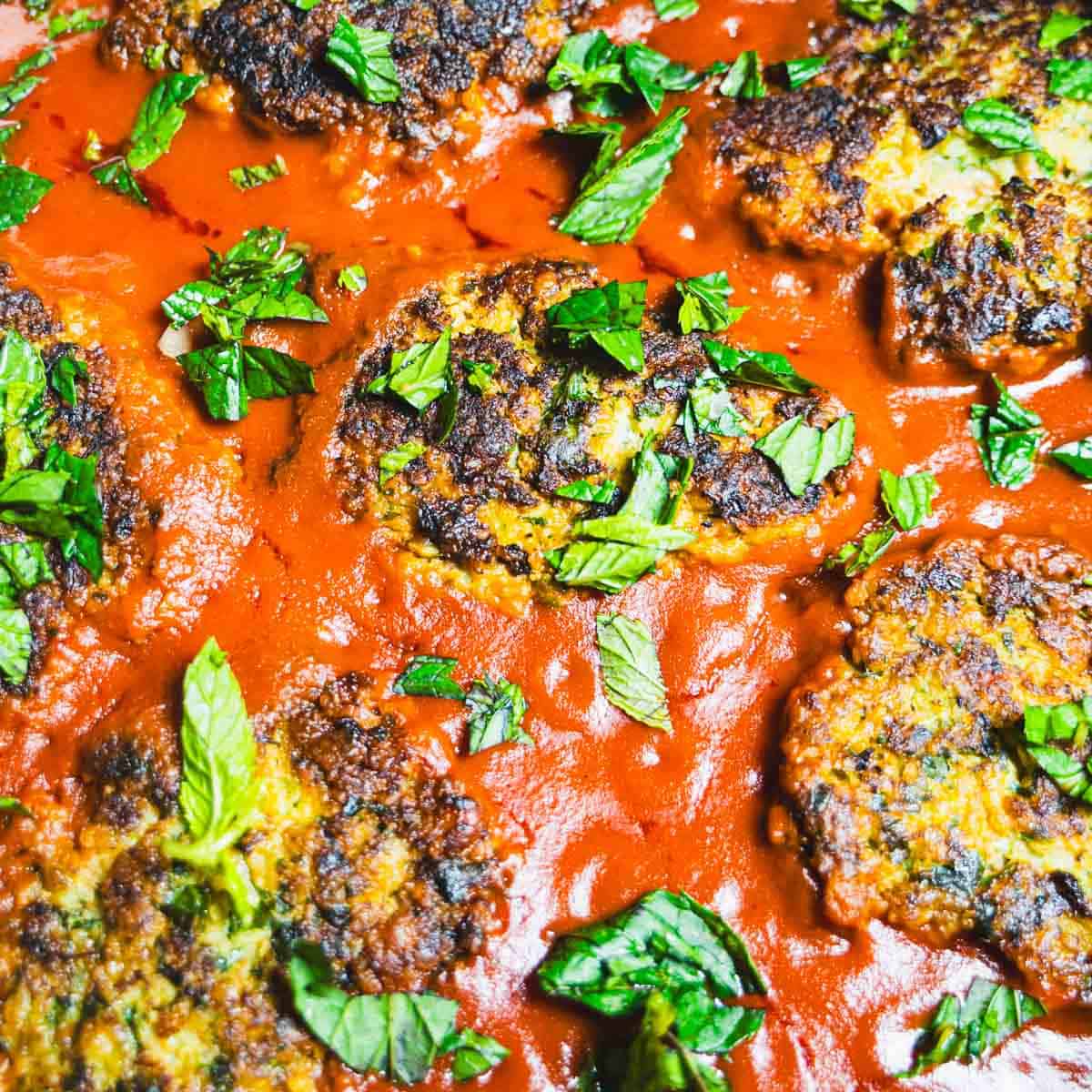 Cod cakes in tomato sauce sprinkled with chopped mint.