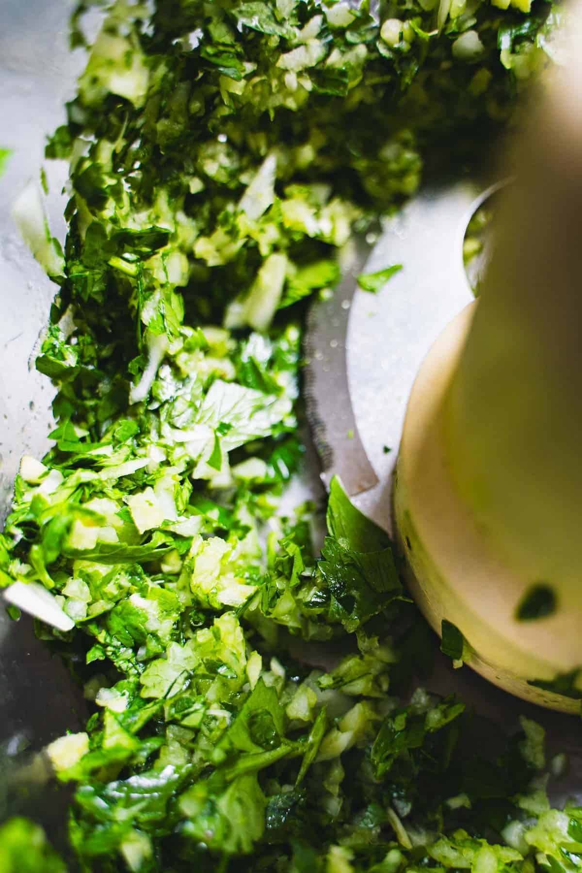 fresh herbs, onion and garlic in bowl of food processor chopped finely for cod cakes.