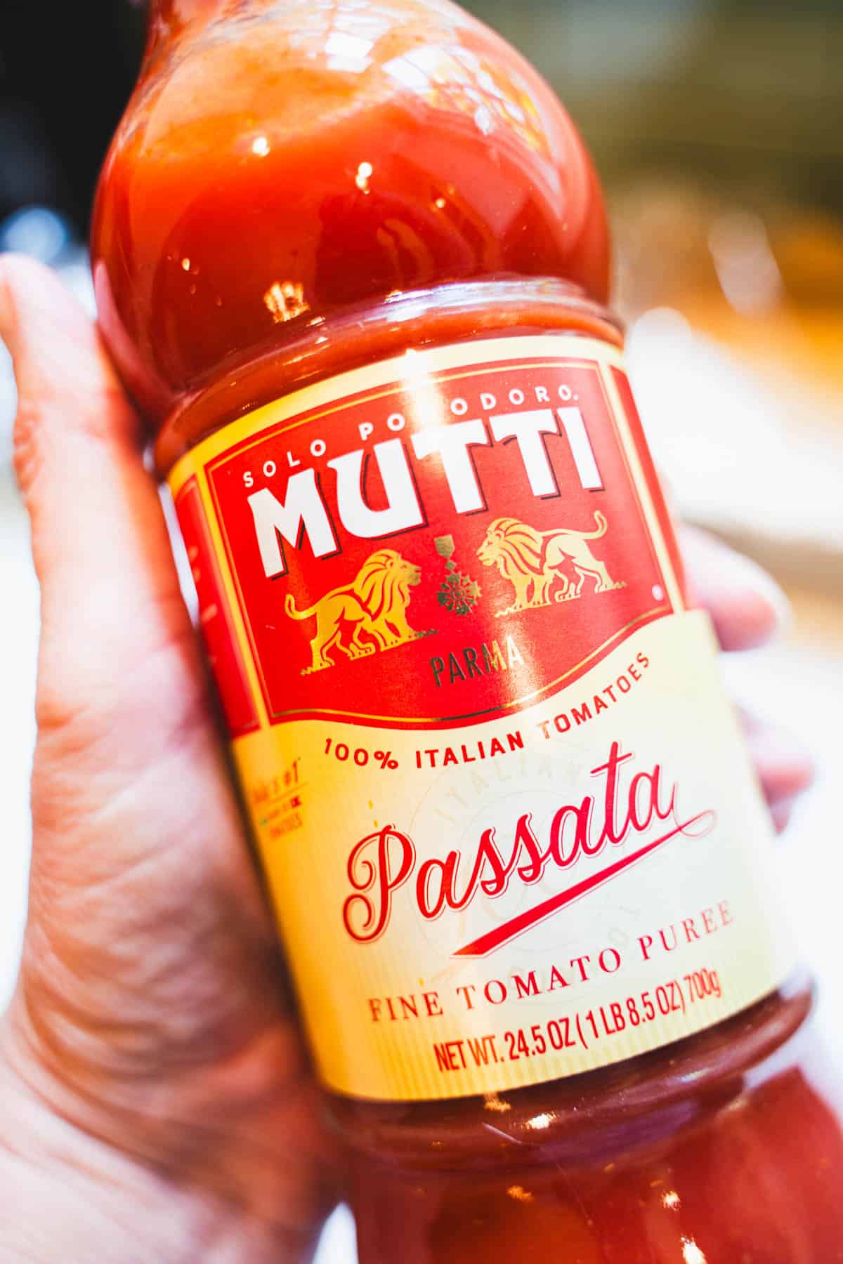 Jar of Passata, to make cod cakes in tomato sauce held in a hand.