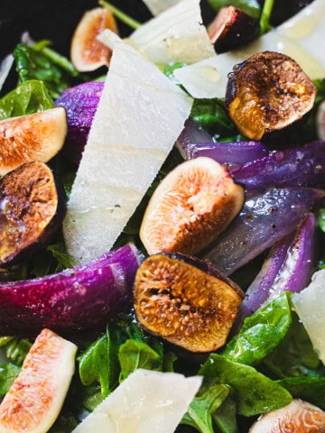 Fig salad with white balsamic dressing and shaved pecorino in a black bowl.