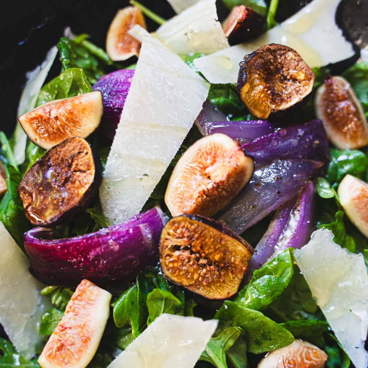 Fig salad with white balsamic dressing and shaved pecorino in a black bowl.