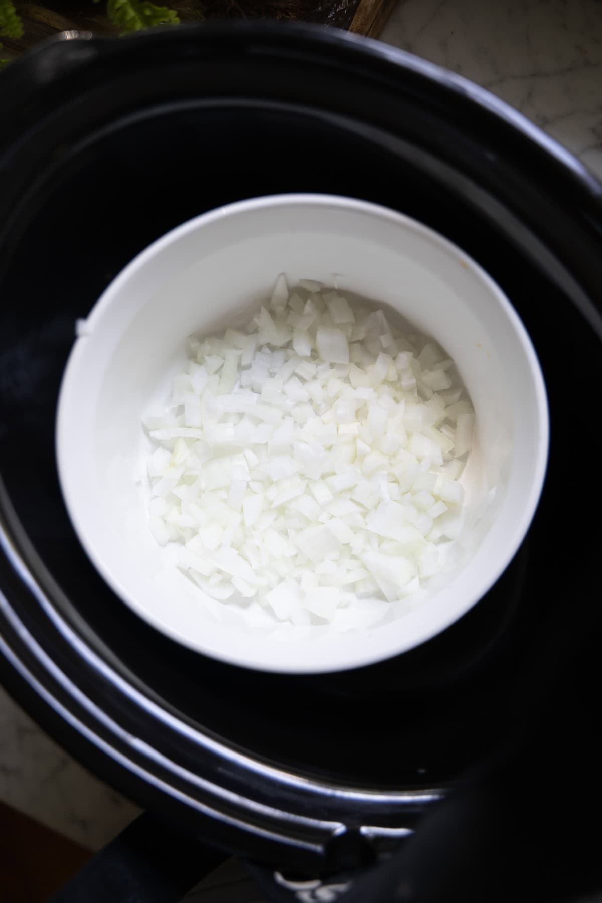 Onion layer in a small baking dish inside a large slow cooker bowl.