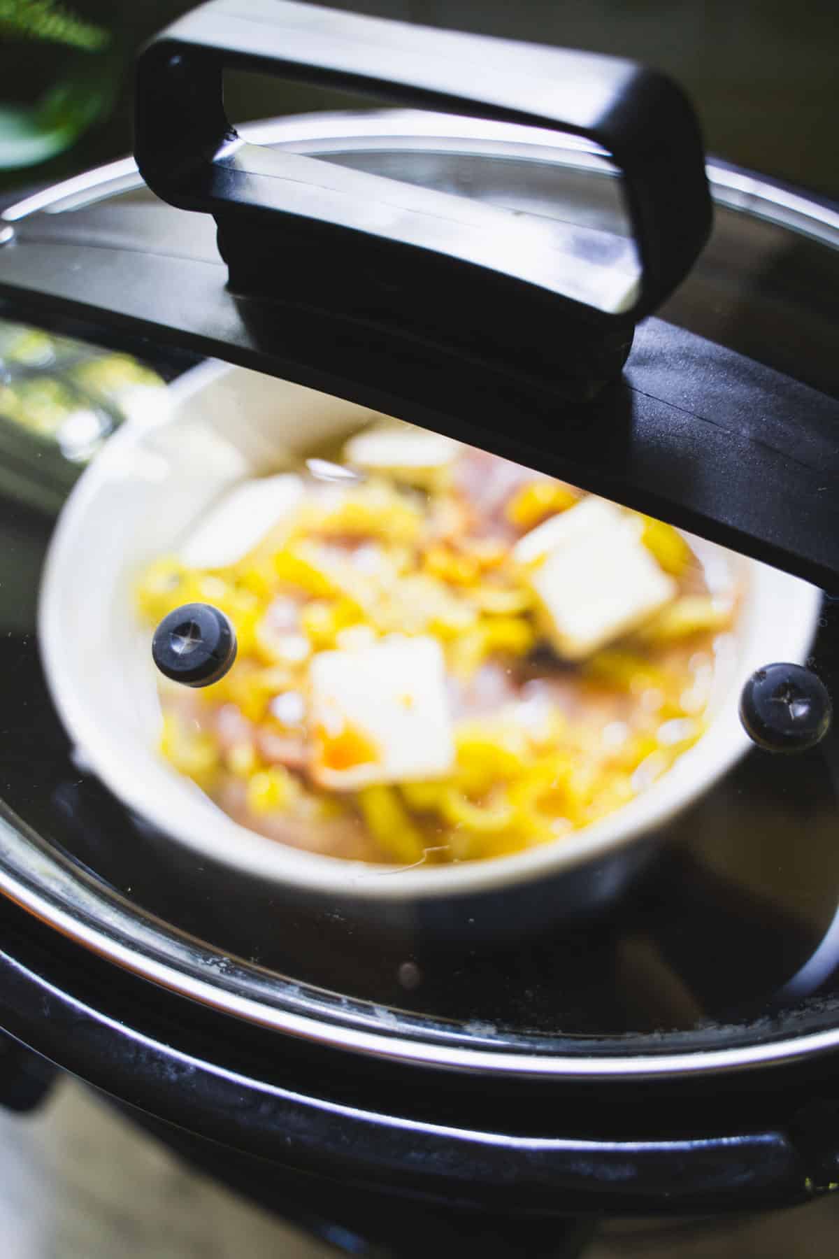 Mississippi Chicken inside a small oven safe baking dish placed inside the large oval slow cooker bowl.