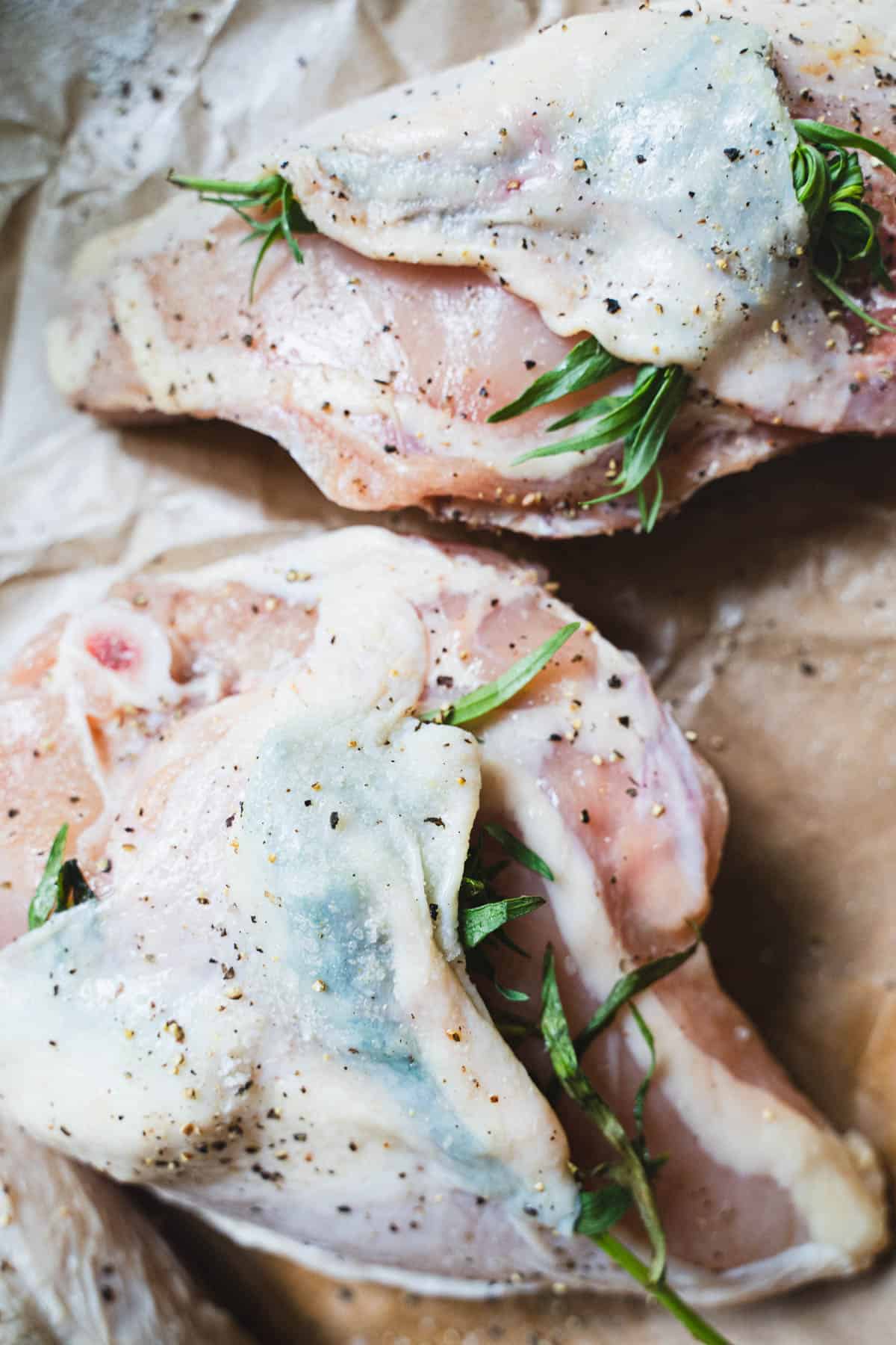 Bone in, skin on chicken breasts with tarragon sprigs tucked under skin.
